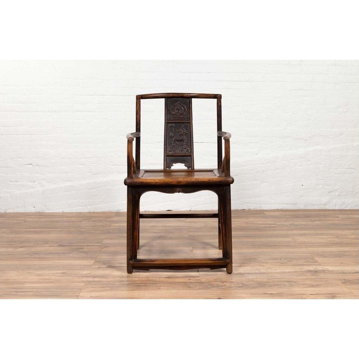 Brown elmwood chair with Chinese Ming Dynasty design on wooden floor against a white wall indoors.