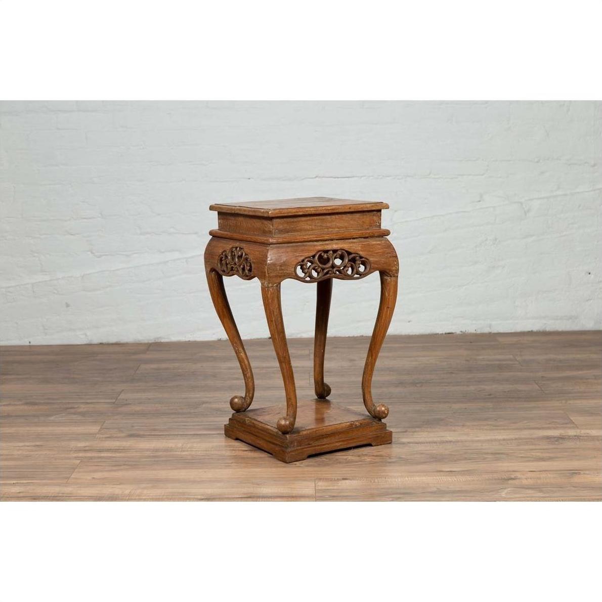 Dark wood Ming style incense stand with cabriole legs and carved apron, indoors against a white brick wall.
