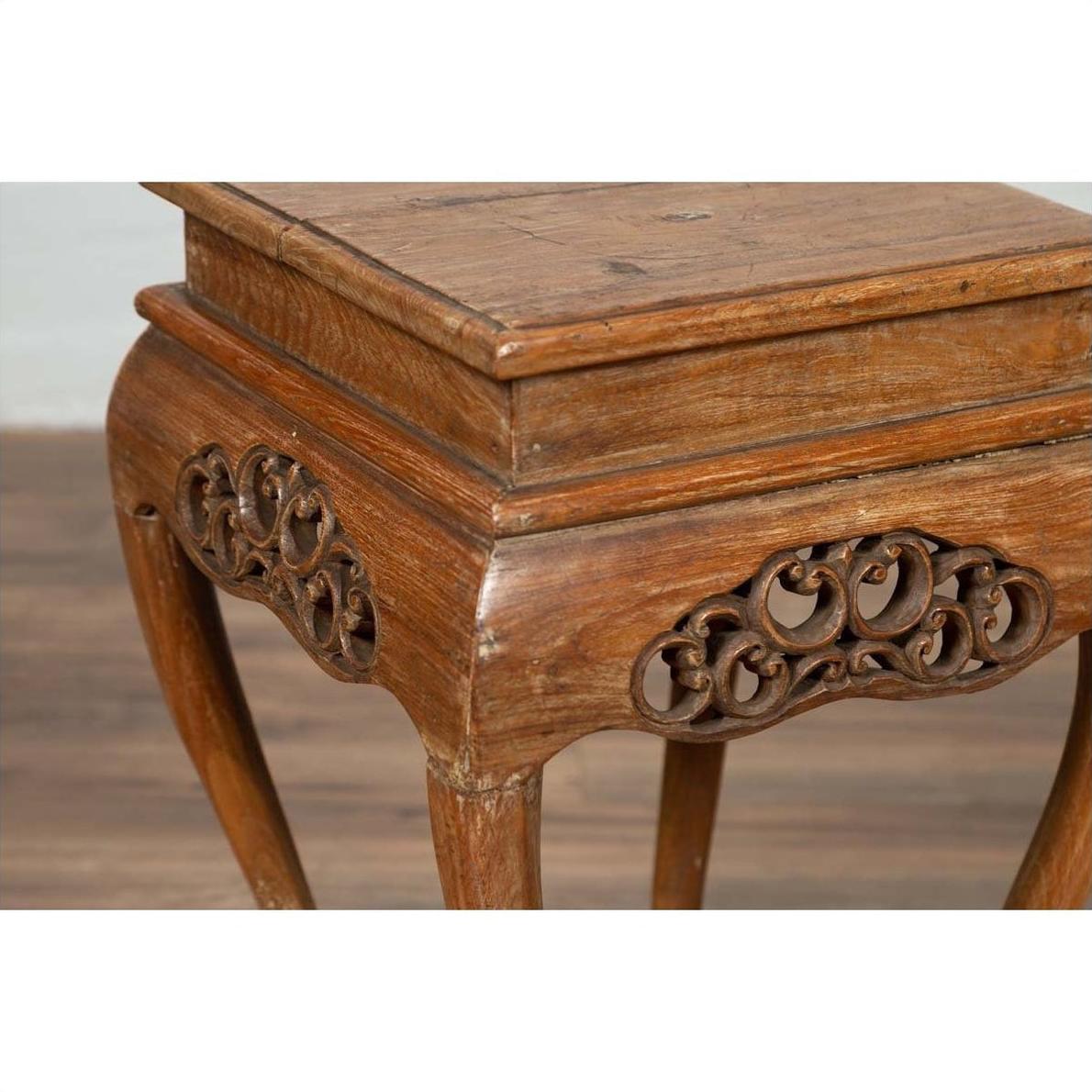 Close-up of a dark wood Ming style incense stand with cabriole legs and carved apron, on a wooden floor indoors.