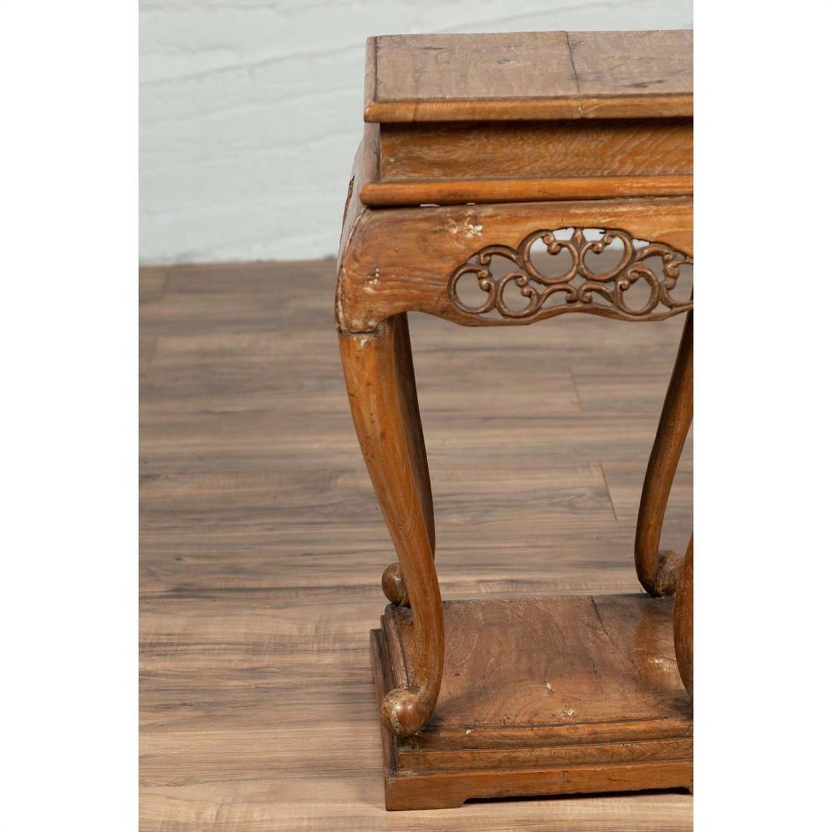 Close-up of a dark wood Ming style incense stand with cabriole legs and carved apron on a wooden floor.