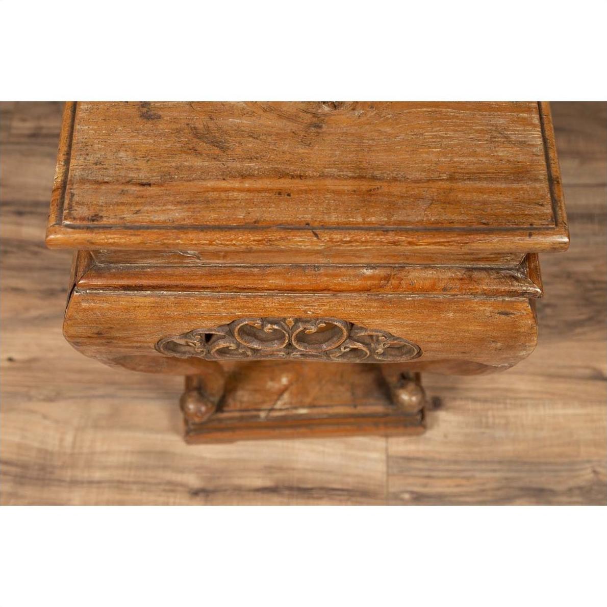 Brown wooden incense stand with cabriole legs and carved apron on rustic wooden floor.