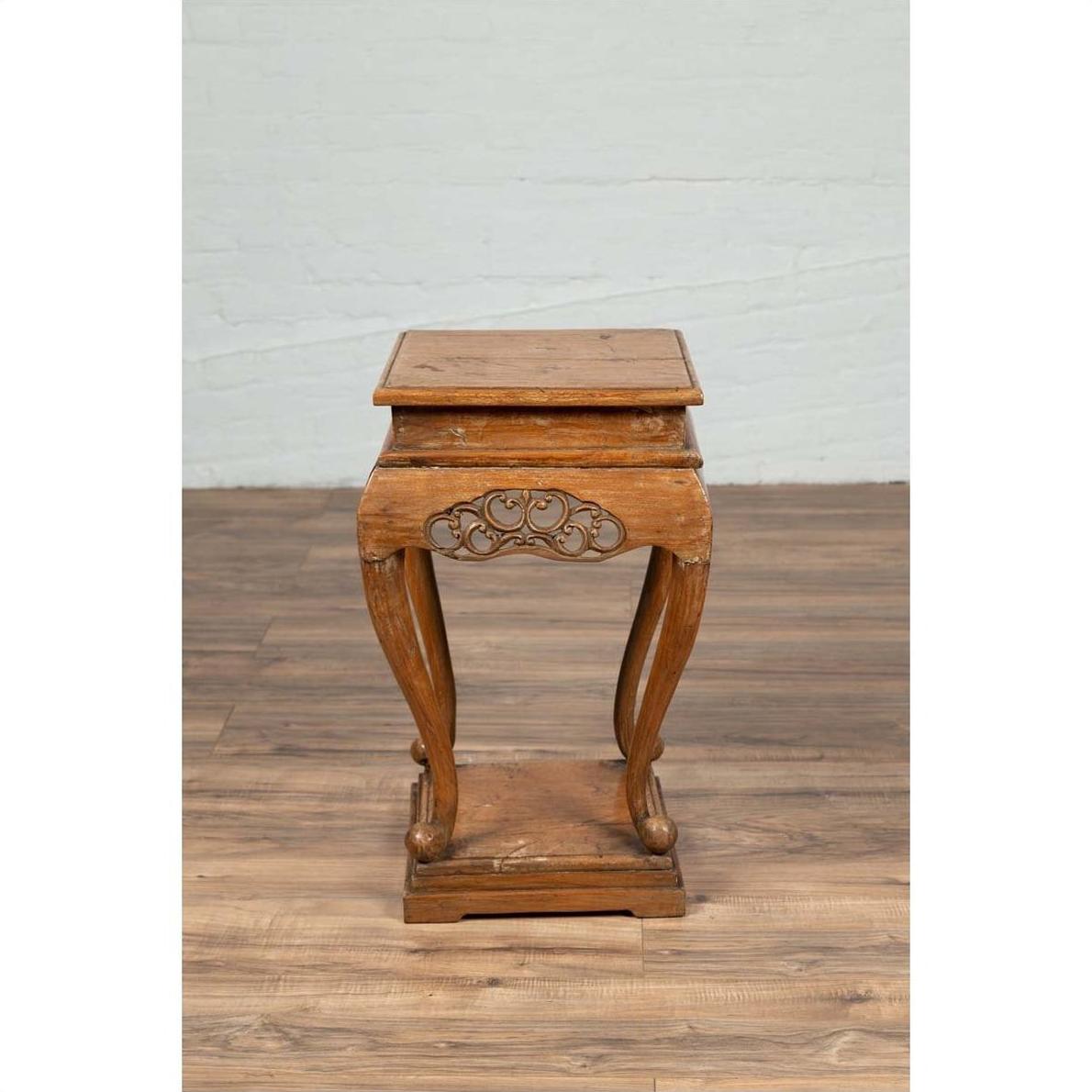 Brown wooden Ming style incense stand with cabriole legs and carved apron, shown on a wooden floor indoors.