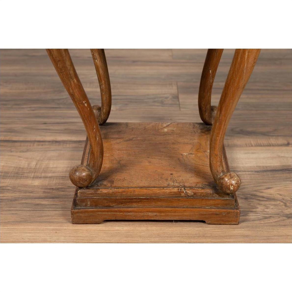 Close-up of brown wooden Chinese Ming style incense stand with cabriole legs and carved apron on wood floor.