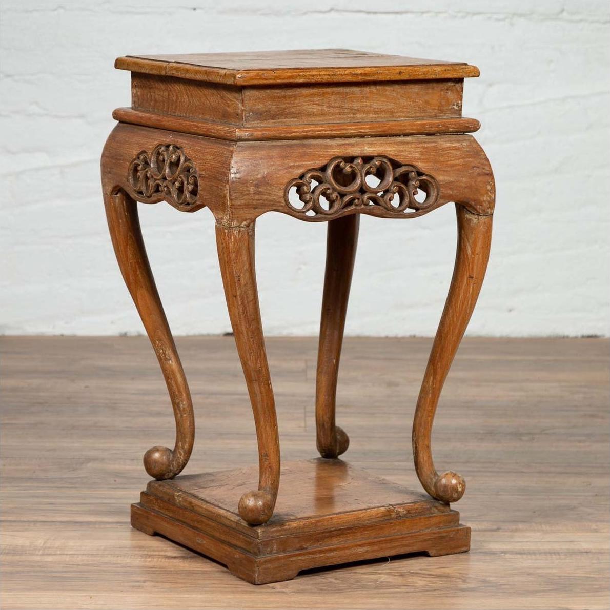 Brown wooden incense stand with cabriole legs and carved apron, placed on a wooden floor by a white brick wall indoors.