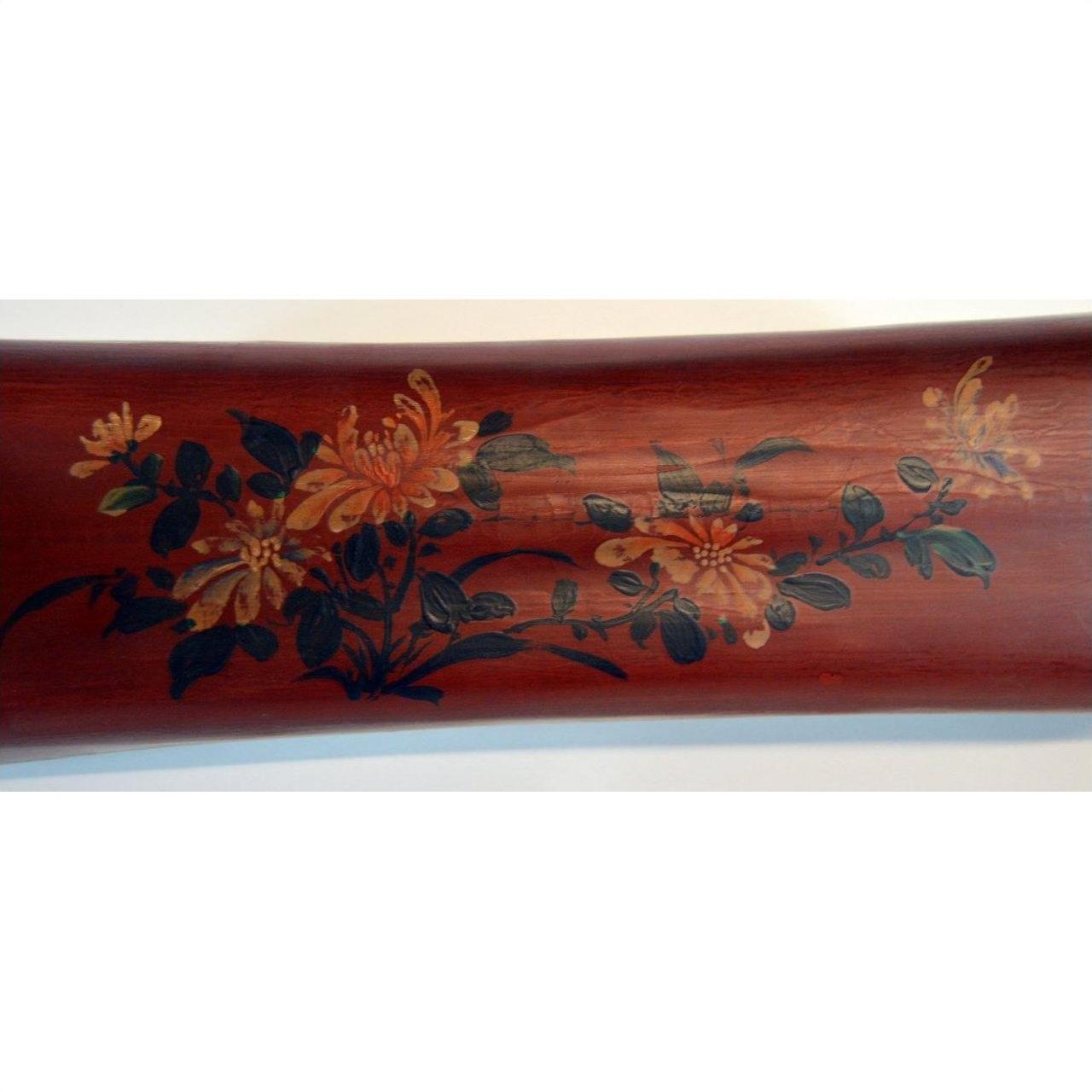 Brown lacquered wood opium pillow with yellow, orange, and green painted floral design, leather accents, close-up.