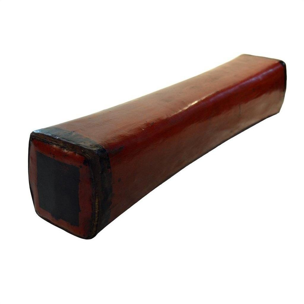 Rectangular red lacquered Chinese opium pillow with black ends on a white background.
