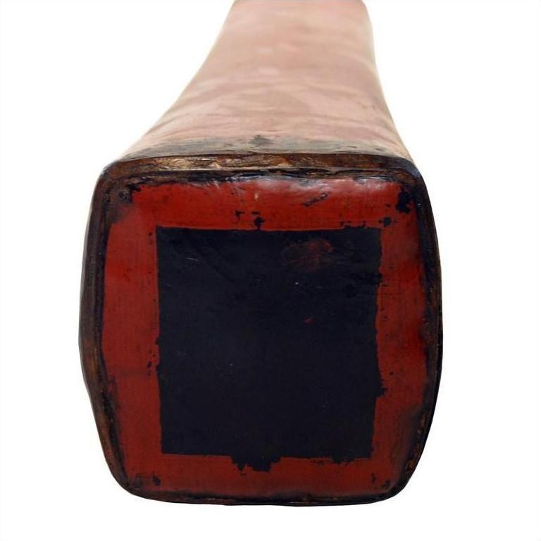 Close-up of red lacquer tip on square end of Chinese opium pillow, ceramic, against white background.