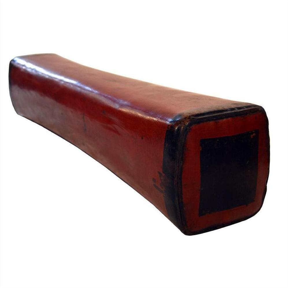 Rectangular red lacquered Chinese opium pillow with black ends on a white background.
