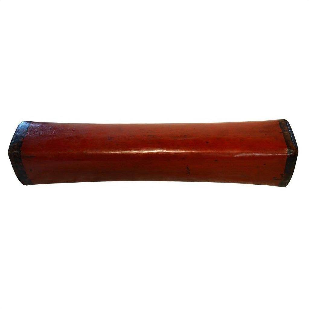 Curved red lacquer Chinese opium pillow with black ends, rectangular shape, close-up on a white background.