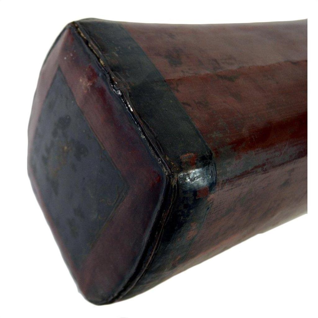 Close-up of a rectangular dark brown leather opium pillow with worn edges and visible stitching.