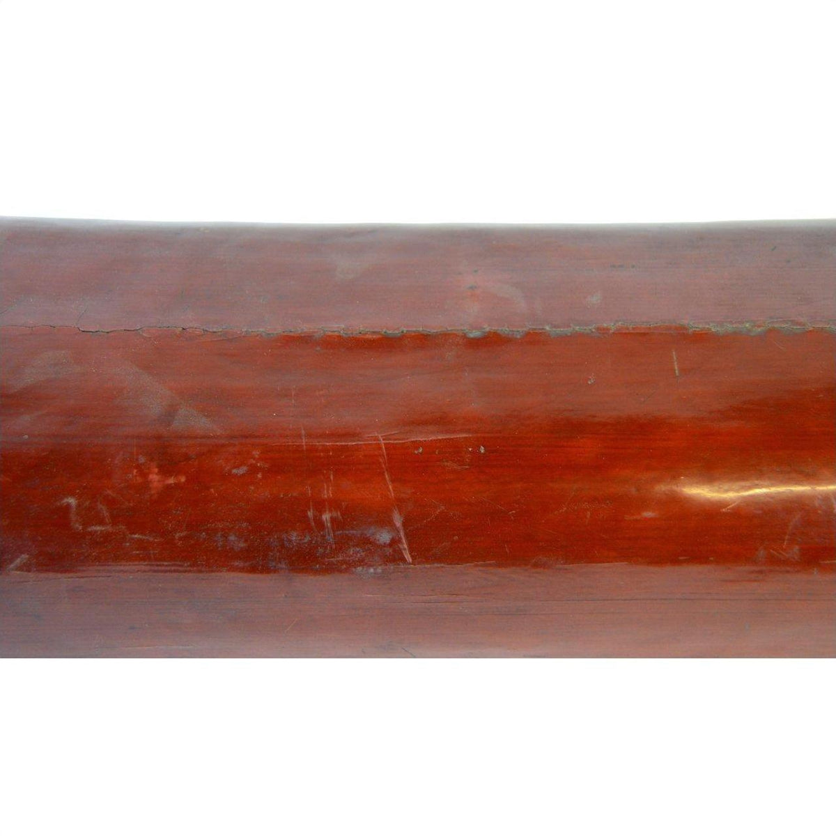 Close-up of a polished brown wooden Antique Opium Pillow on a wood surface with visible grain and scratches.