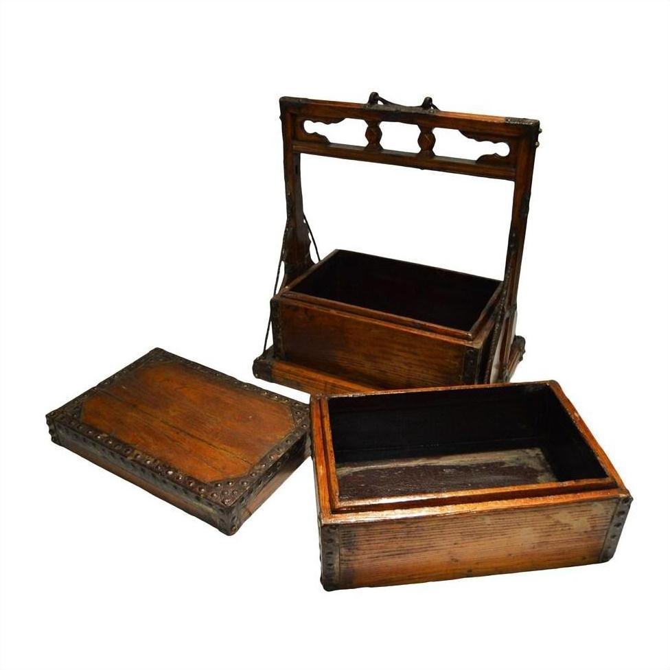 Brown wooden Chinese picnic boxes, one with a carved handle, two open with lids beside them on a flat surface.