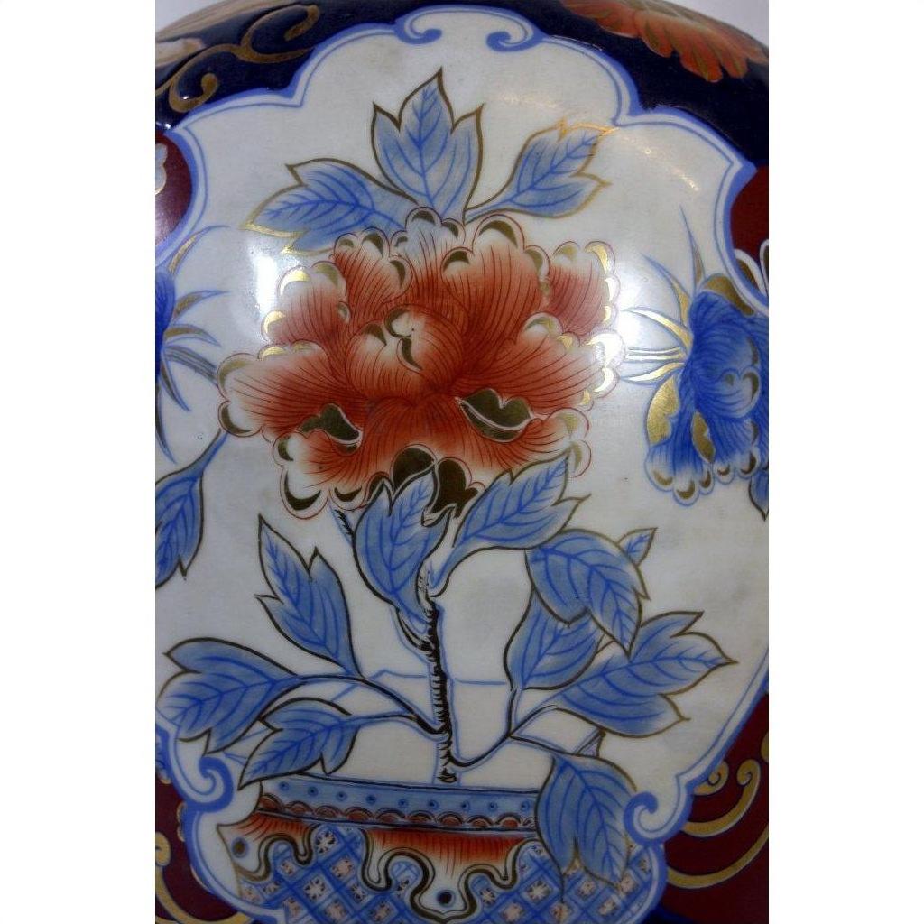 Close-up of Chinese porcelain electric lamp with ornate vase design, large red flower, blue leaves, and gold accents.