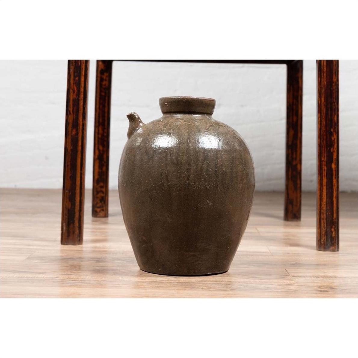 Blue glazed ceramic water jug with petite spout on wooden floor beneath a table, Qing Dynasty, 19th century.