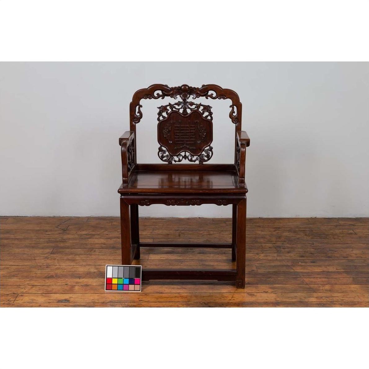 Dark rosewood Chinese chair with carved backrest, 19th century, on wooden floor next to color chart.