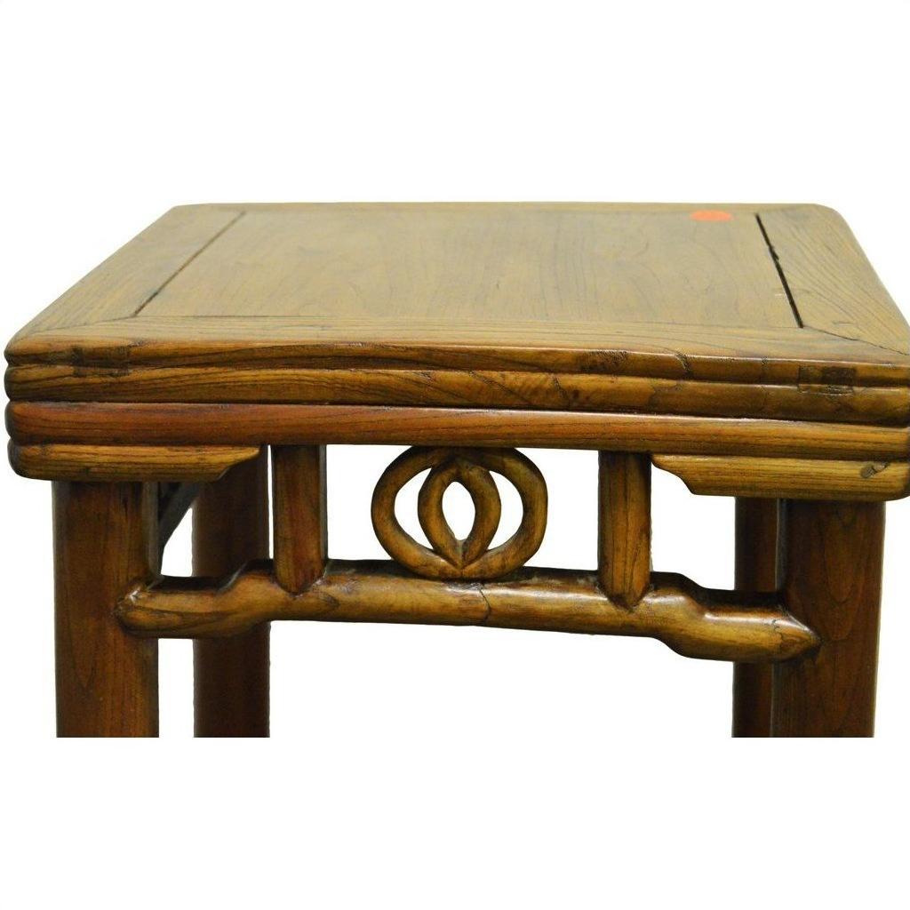 Close-up of a wooden Chinese side table with carved friezes beneath the tabletop.