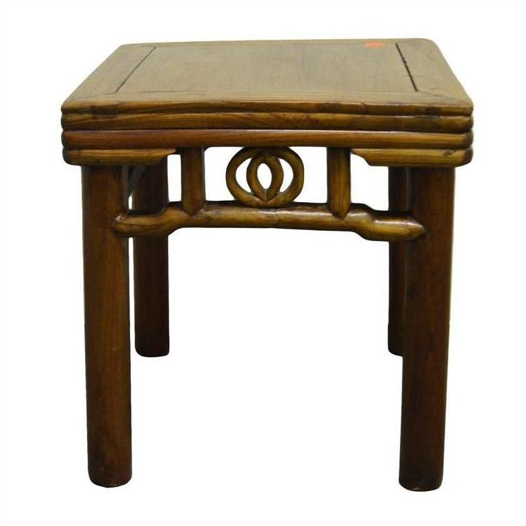 Brown wooden square side table with rounded legs and carved friezes under the seat, close-up view.