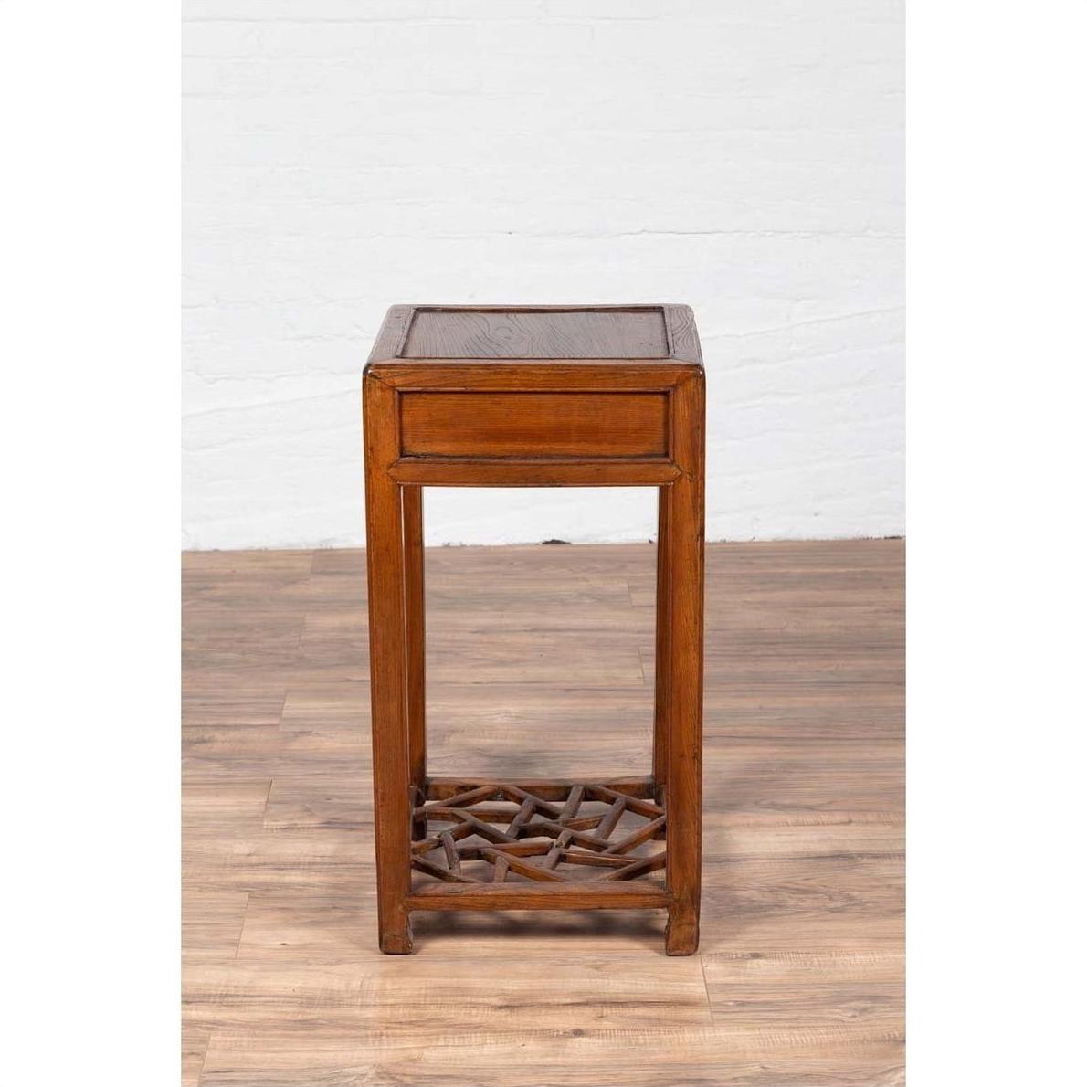 Brown elmwood lamp table with single drawer and cracked ice shelf, tall and narrow design, indoor setting.
