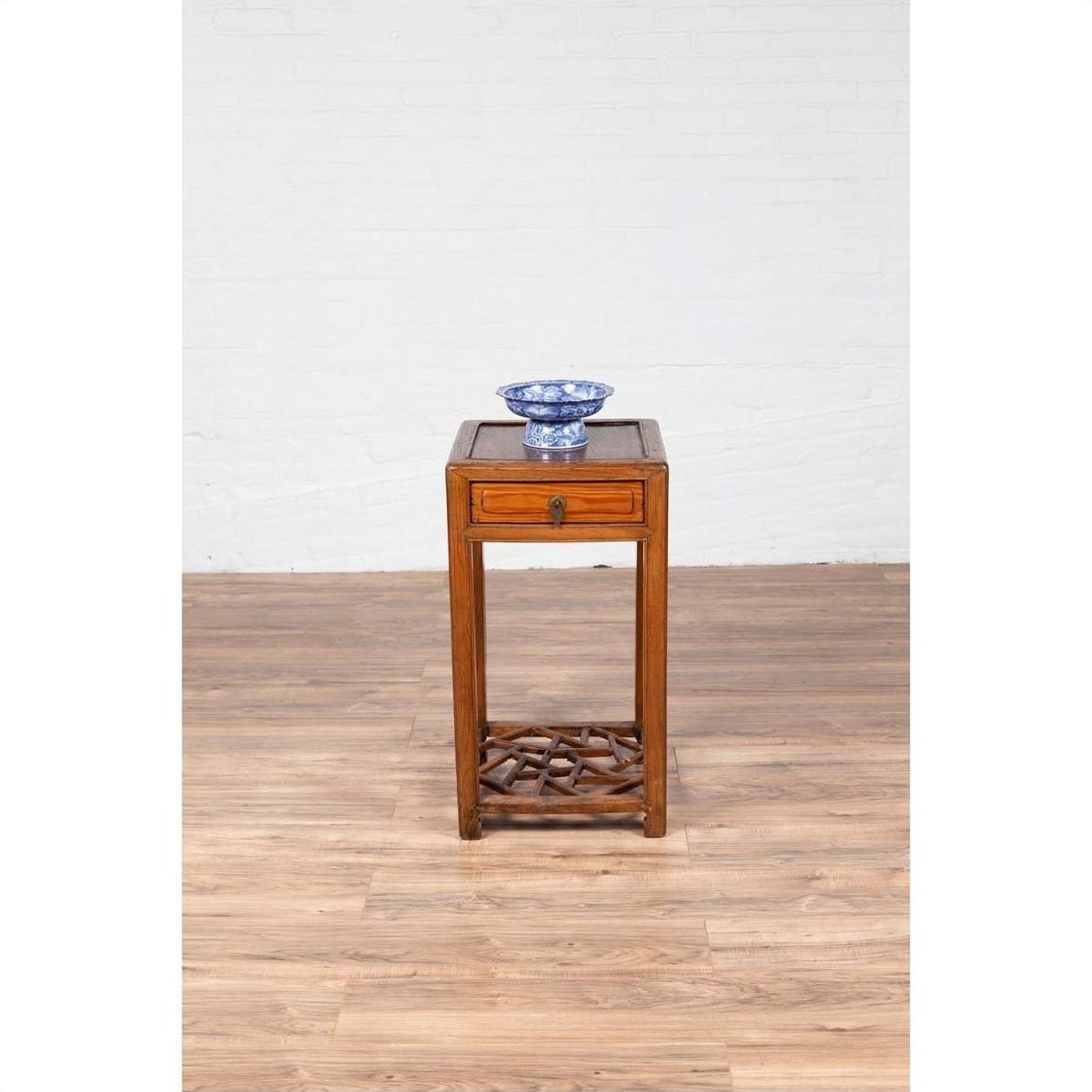 Blue and white ceramic bowl on a vintage elmwood table with single drawer, placed against a white brick wall indoors.