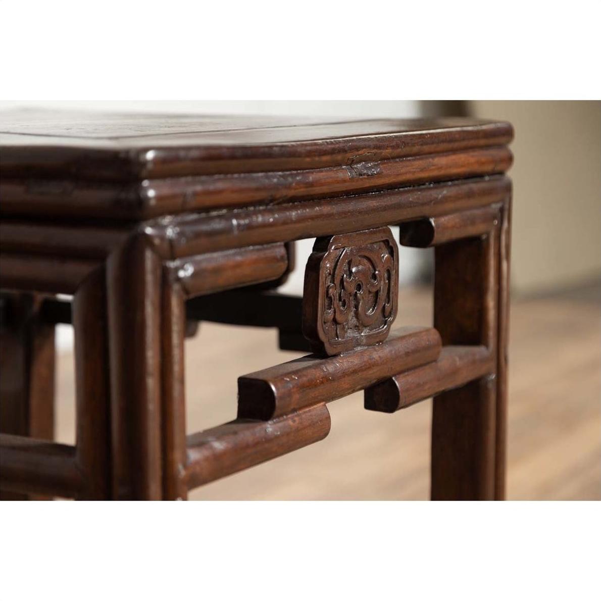 Close-up of dark wood side table with carved medallions and smooth corner, vintage Qing style.