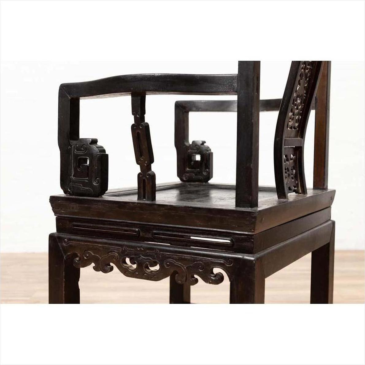 Close-up of a dark wood Chinese wedding chair with curvy pierced splat and serpentine arms.