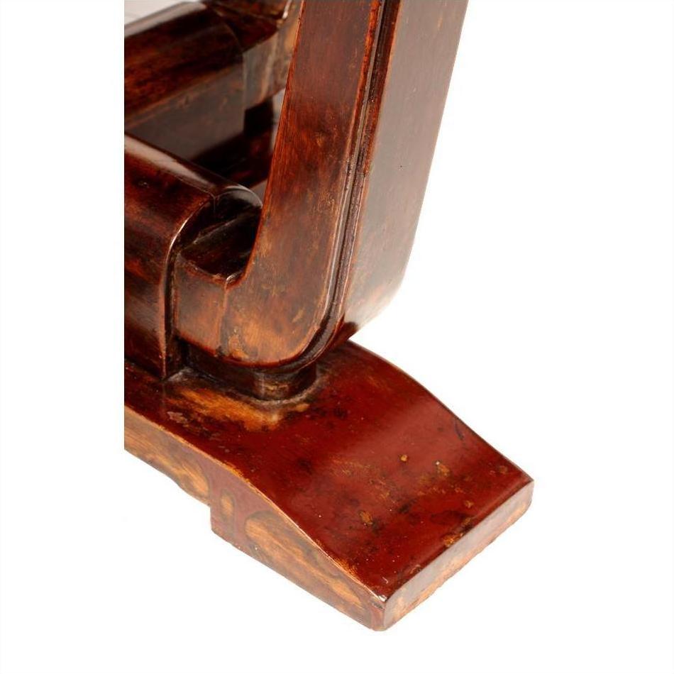 Close-up of reddish-brown Elmwood leg of circular side table showing wood grain and joinery details.