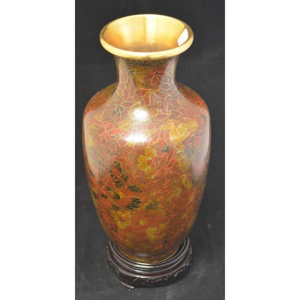 Red and gold cloisonné vase with a wide gold rim and floral pattern, on a dark round base. Close-up view.
