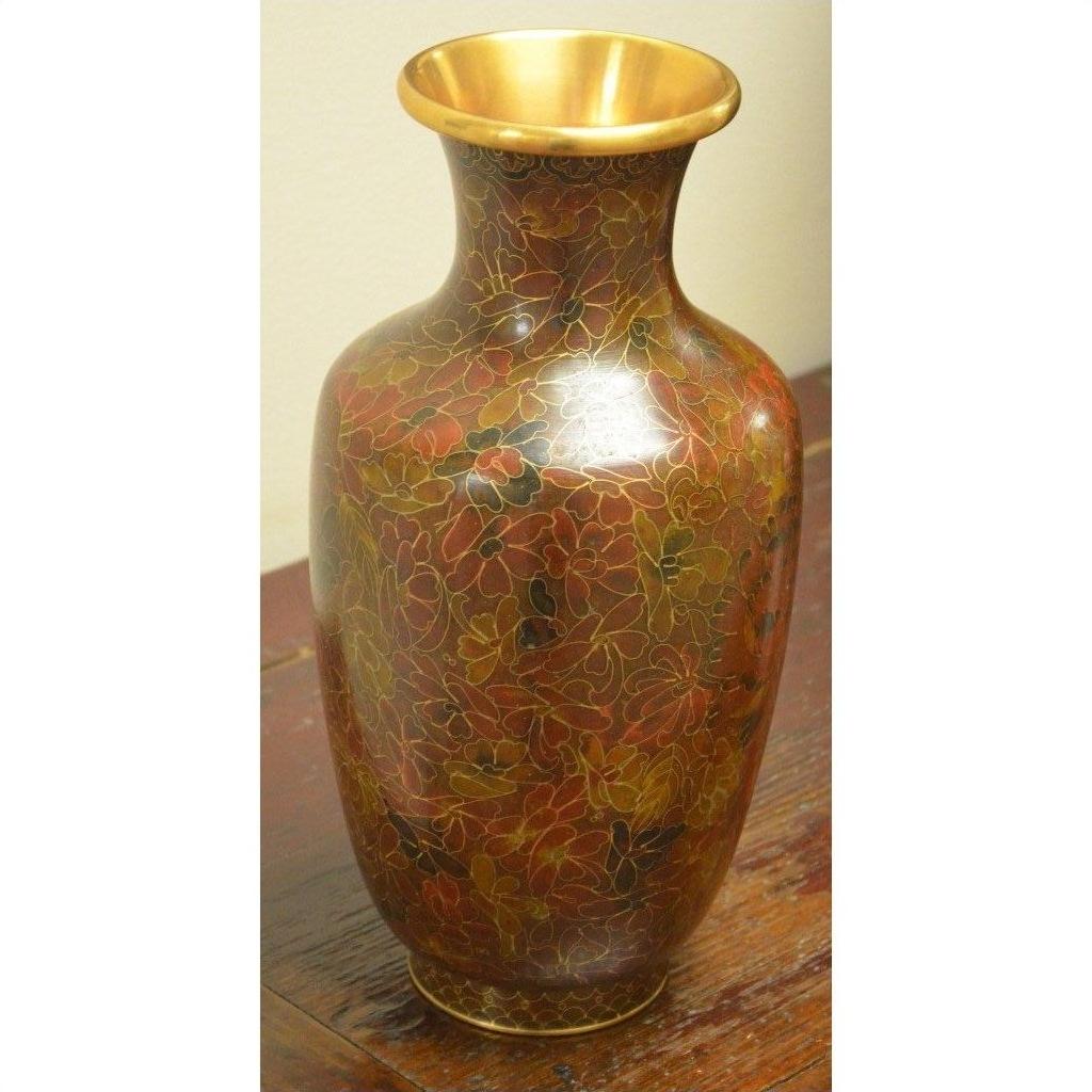 Close-up of a red and gold cloisonné vase with floral patterns on a wooden surface.
