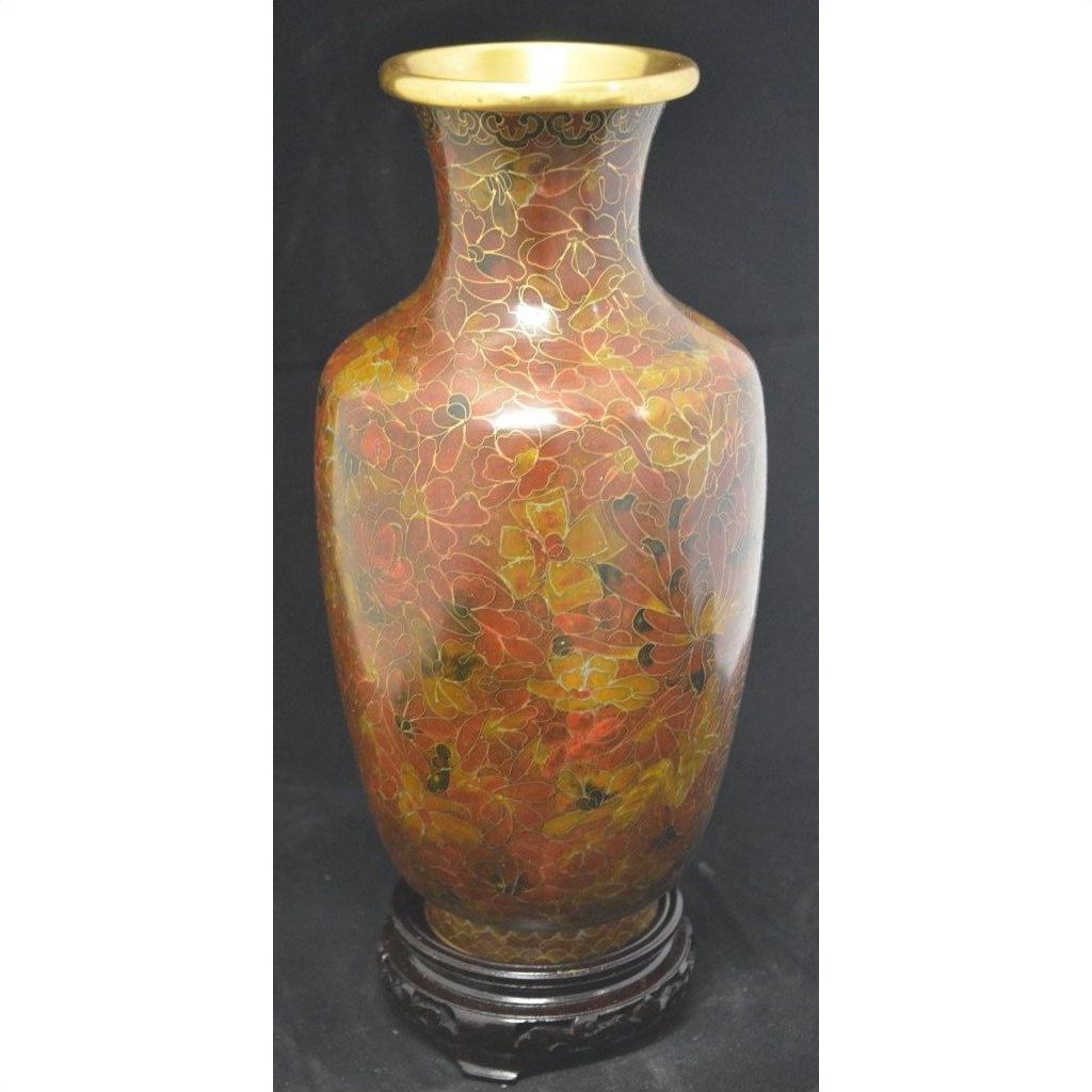 Red, gold, and brown cloisonné vase with floral patterns on a dark wooden stand, close-up view.