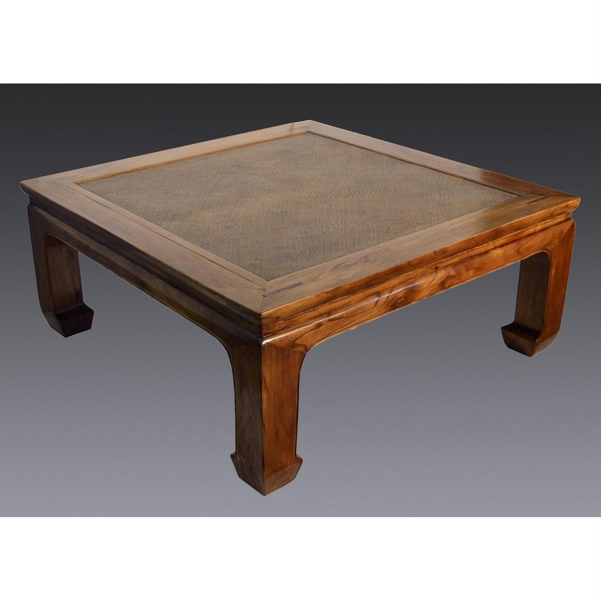 Light rattan coffee table with lacquer finish and curved legs on a gray background.