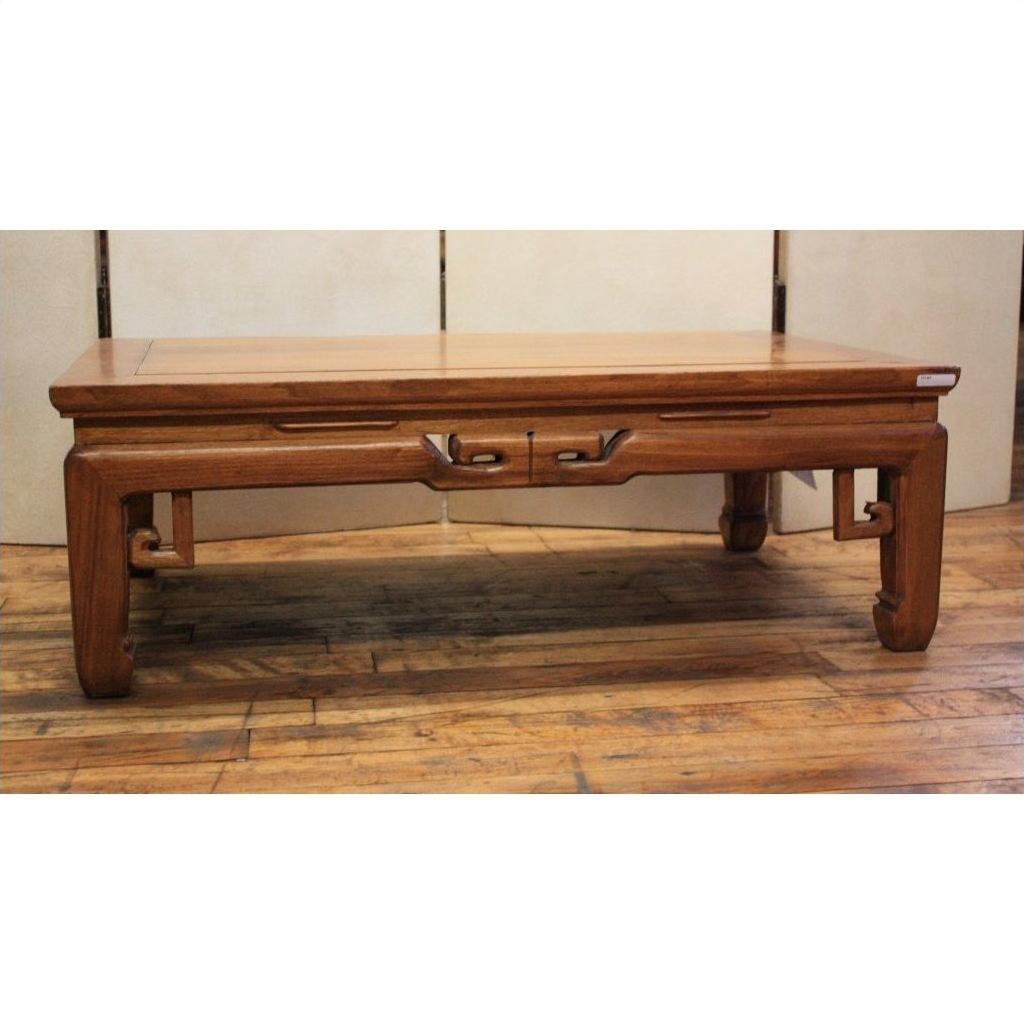 Brown wood coffee table with openwork aprons, two drawers, carved legs, and horse hoof feet on wooden floor.