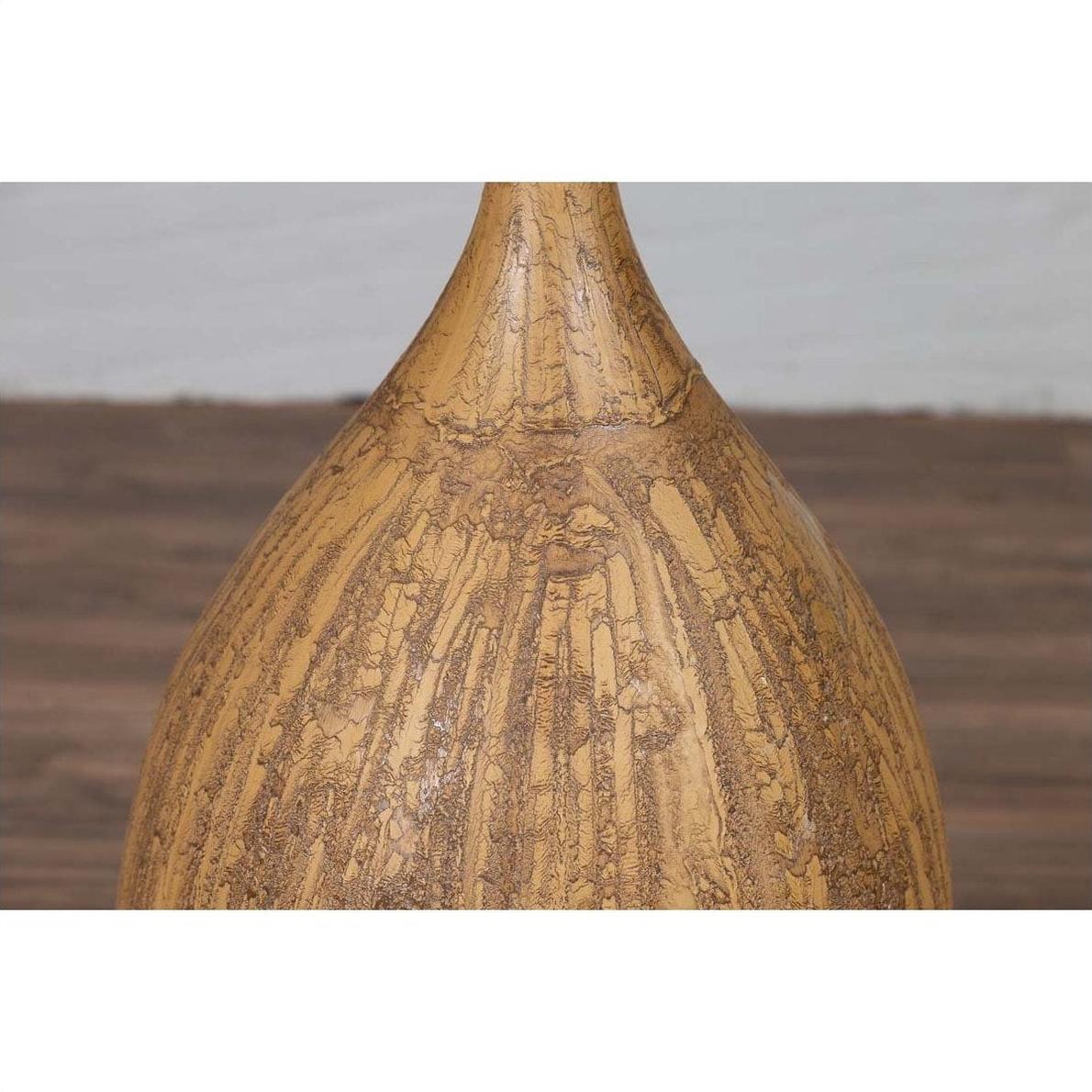 Close-up of mustard glazed ceramic vase with tapered spout, handmade Thai style, on wood surface.