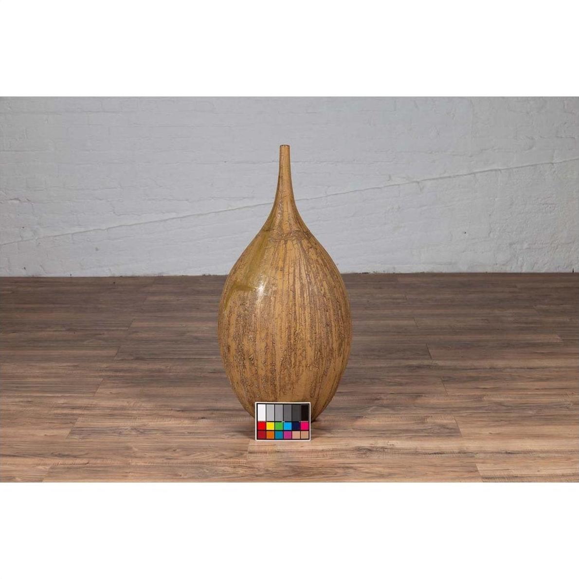 Mustard yellow ceramic vase with tapered spout on wooden floor, color card in front.