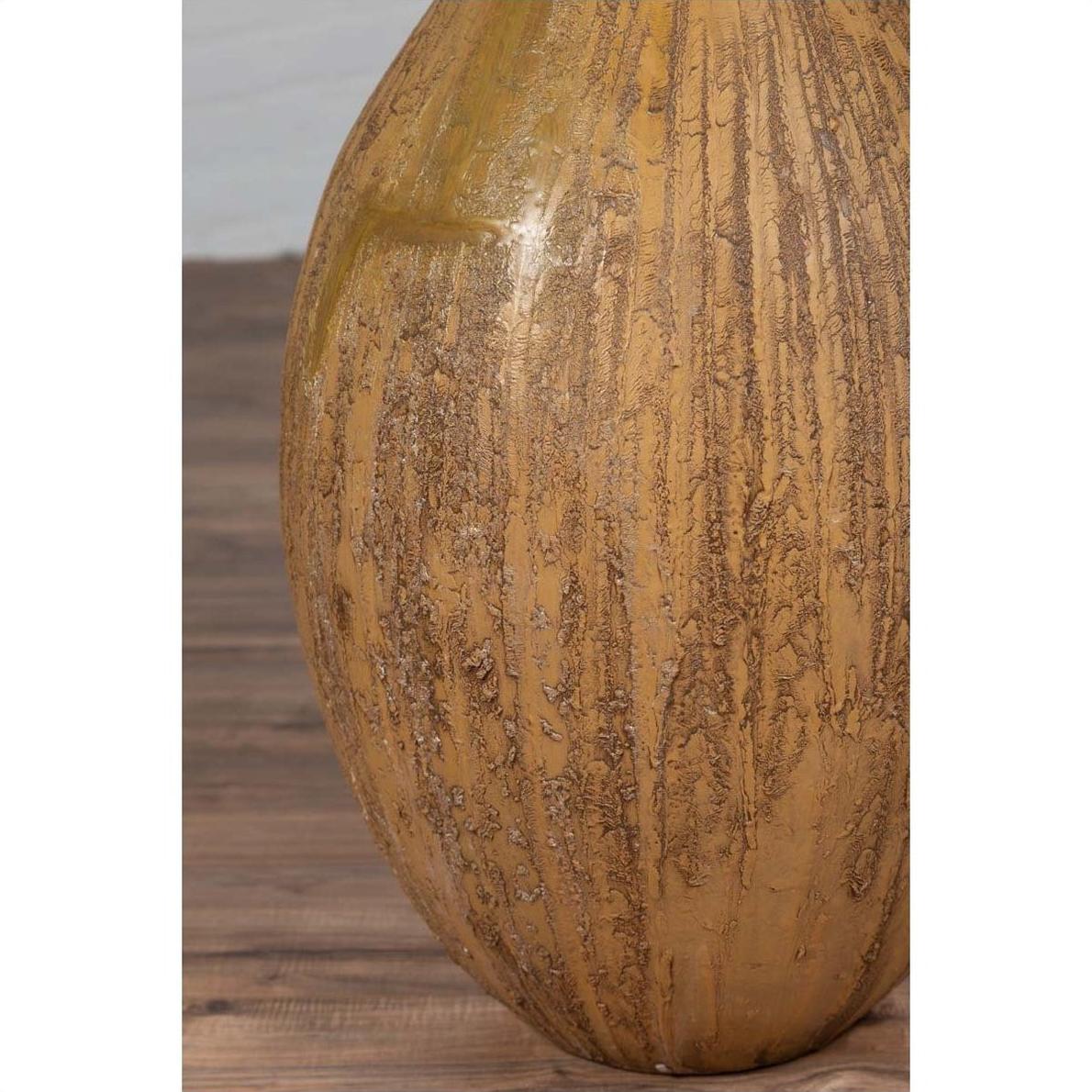 Close-up of mustard ceramic vase with tapered spout on wooden floor.