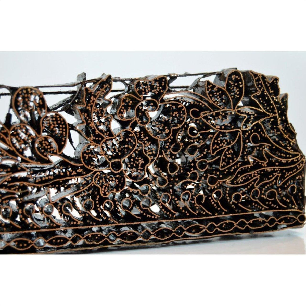 Close-up of copper Batik ink block with intricate floral carvings, used for garment making.