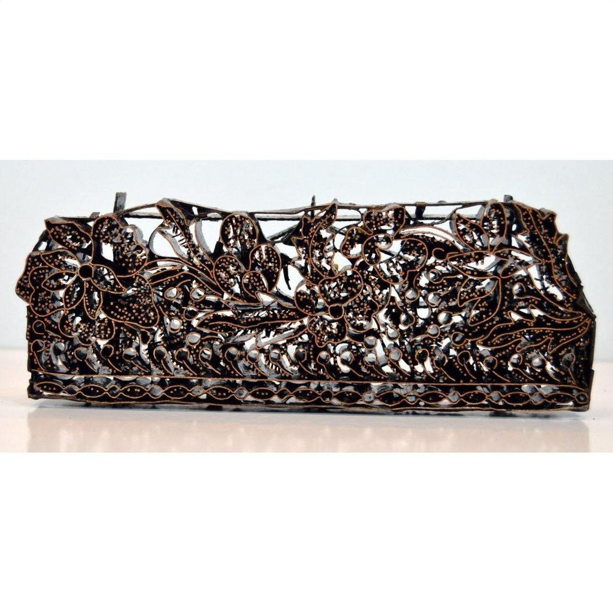 Copper metal rectangular box with intricate openwork floral patterns, close-up on plain background.