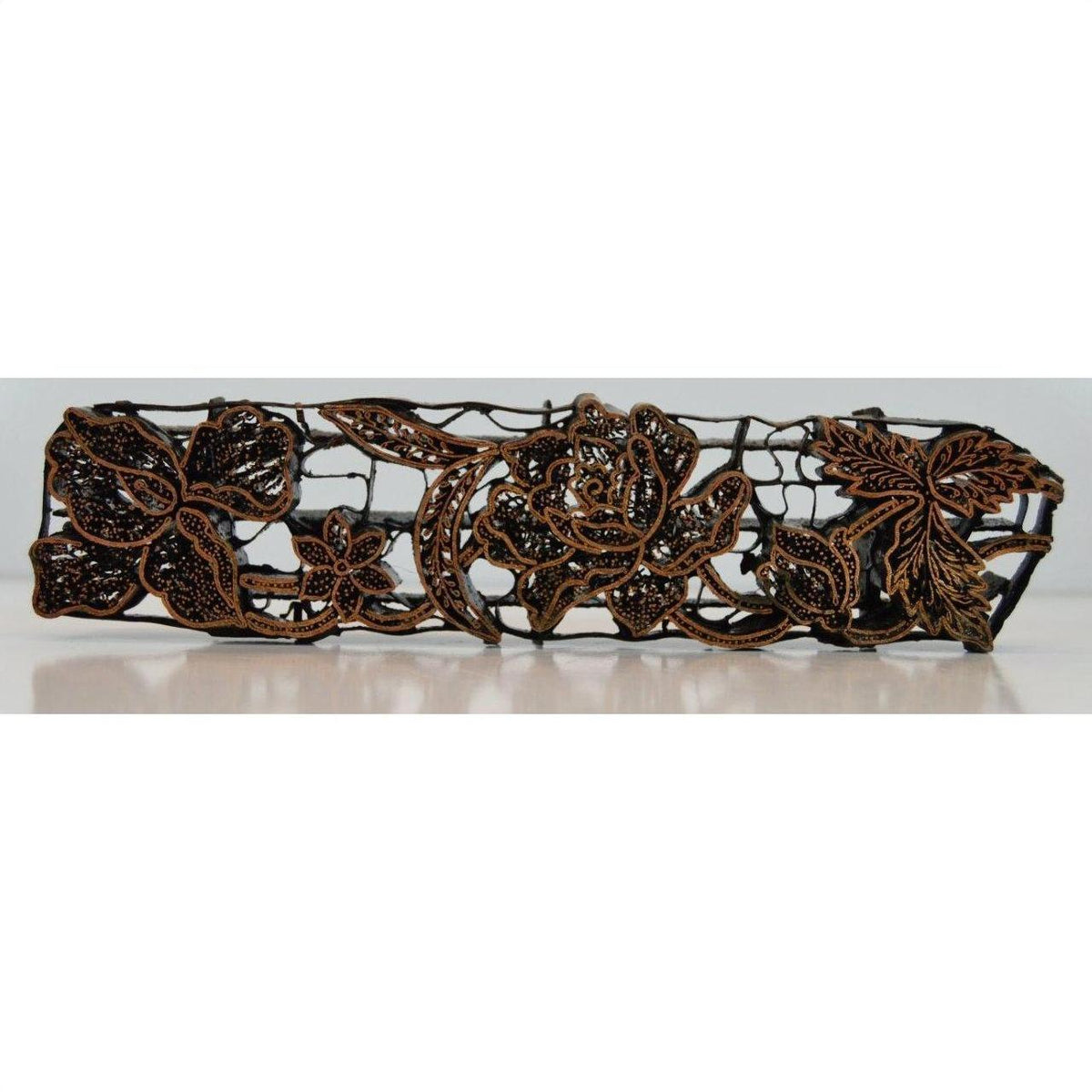 Close-up of dark brown copper barrette with floral and leaf openwork, batik ink block inspired.