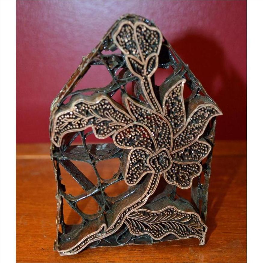 Close-up of copper Batik ink blocks with hand-designed metal ornament and intricate floral patterns on wood.