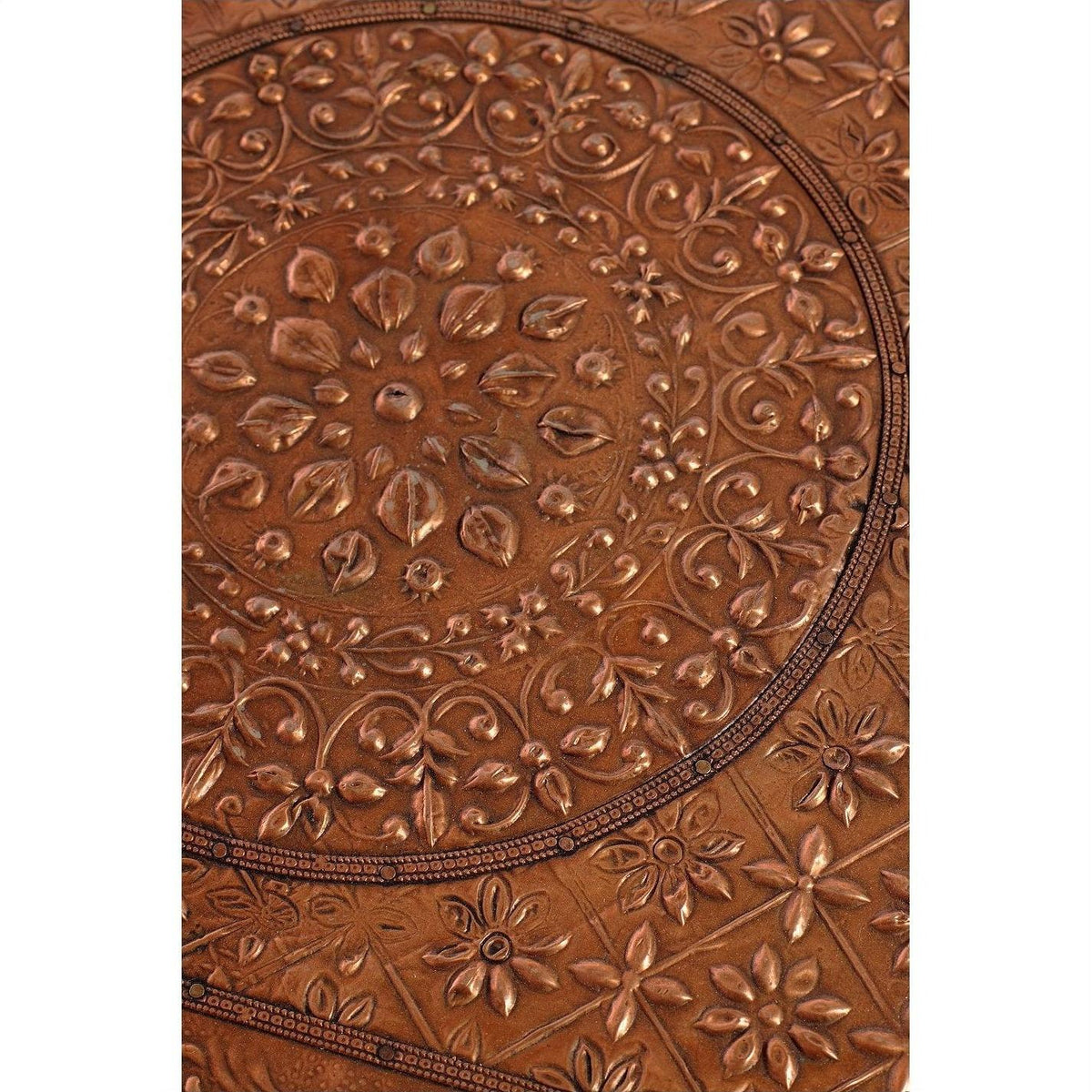 Close-up of copper coffee table surface with embossed intricate floral and geometric patterns.