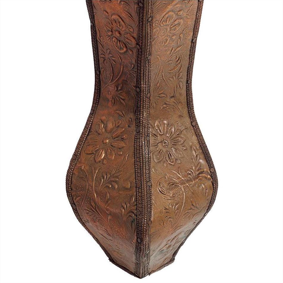 Copper coffee table with ornate embossed floral and leaf patterns on surface, close-up view.