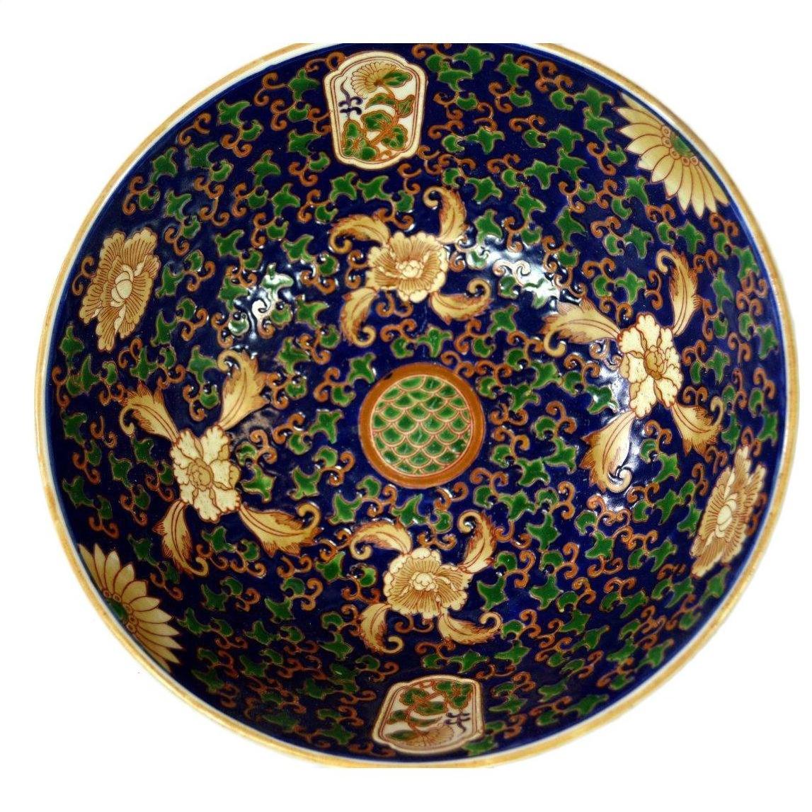 Close-up of blue, green, and gold floral patterned Ming porcelain bowl with central circular design.