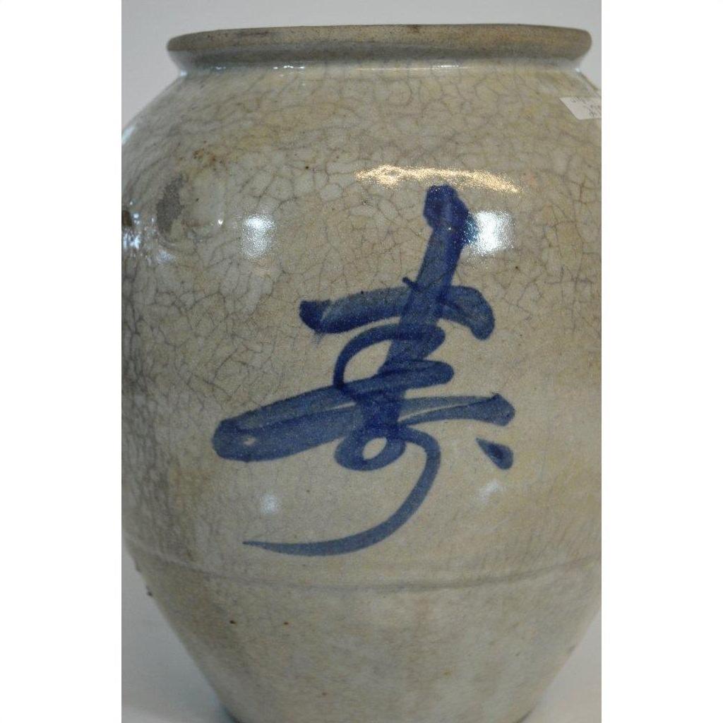 Close-up of white ceramic crackle vase with hand-painted blue Asian calligraphy.