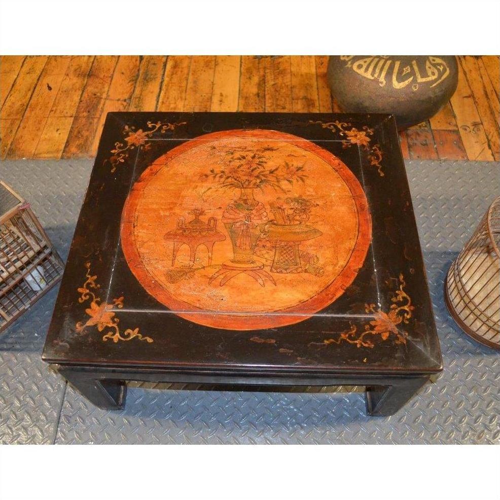 Square wooden Kang table with orange painted central motif and horse hoof feet, close-up.
