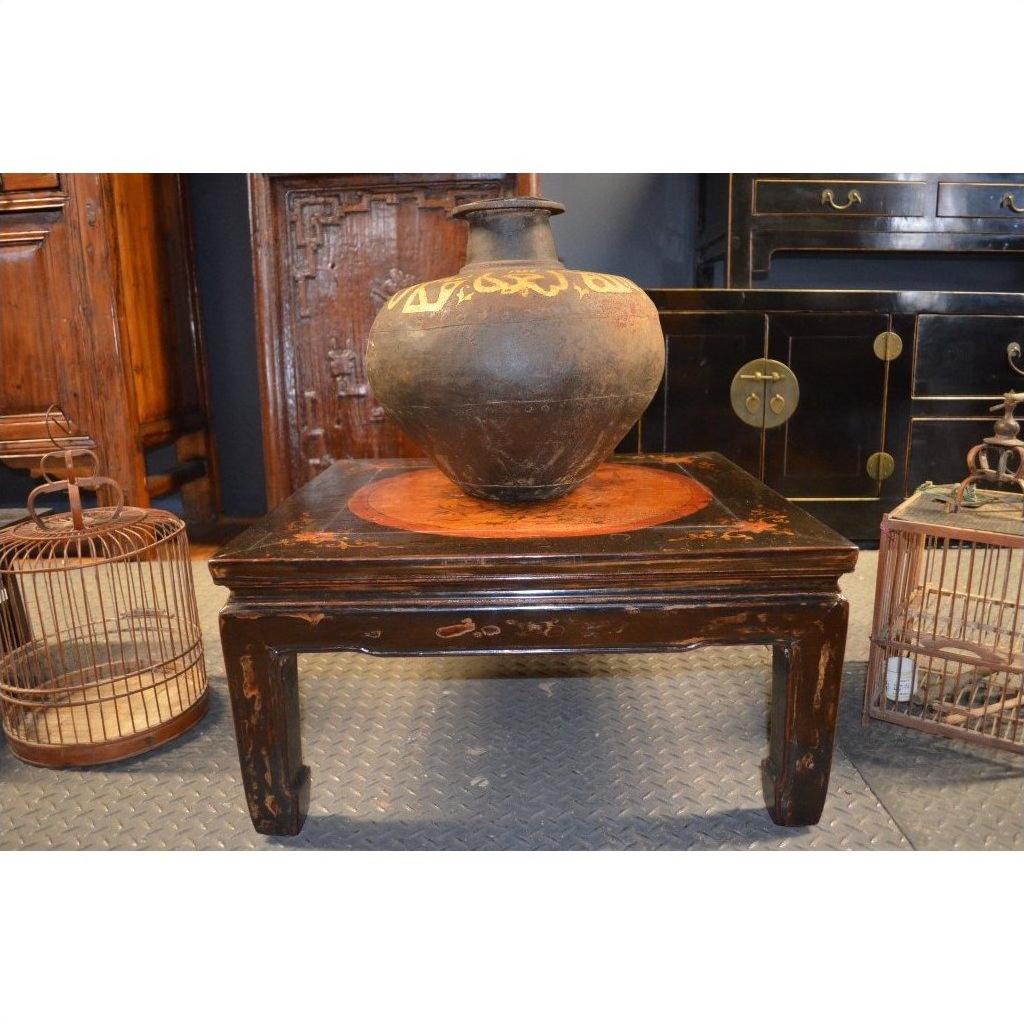 Large ceramic vase on decorated Kang table, with birdcages and dark wooden furniture in the background.