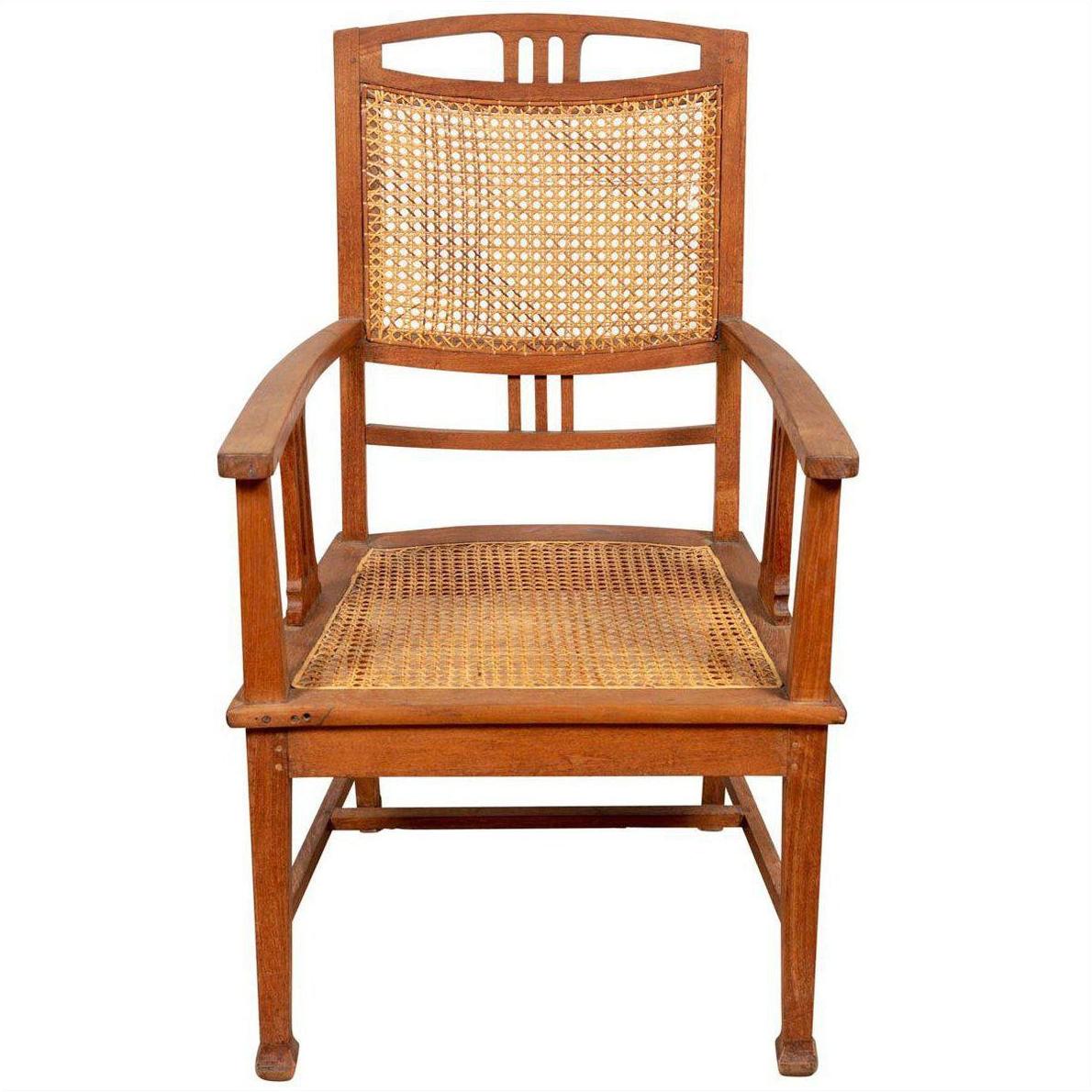 Brown teak Dutch Colonial Javanese armchair with rattan seat and triglyph motifs, front view.