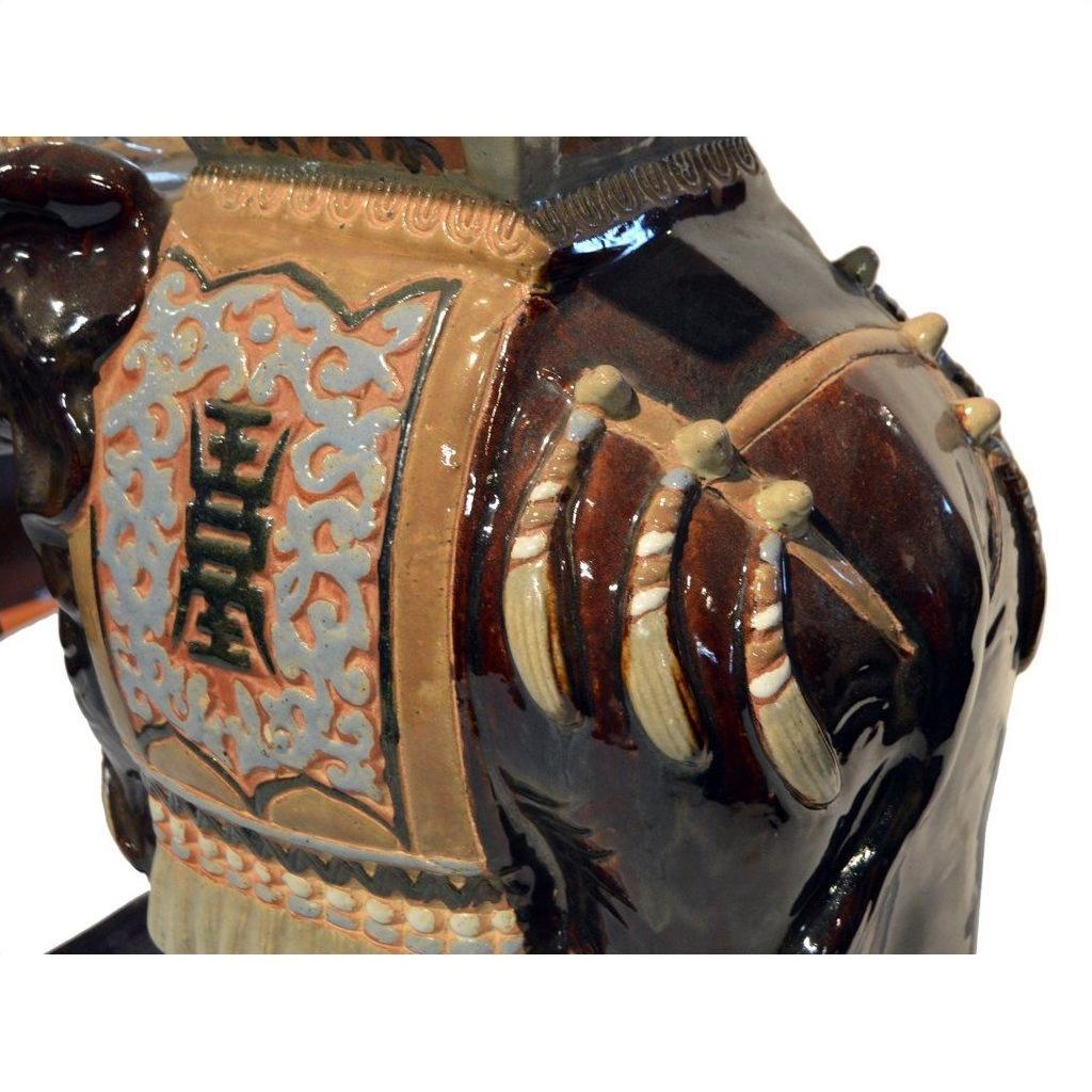 Close-up of a ceramic horse sculpture with ornate saddle beside an earthy-toned Elephant Chinese Garden Stool.