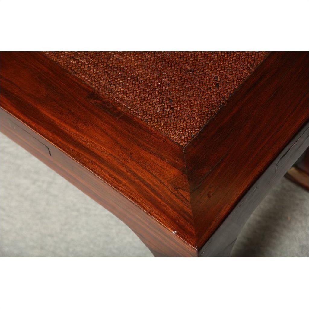 Close-up of dark brown antique elm wood table corner with rattan mat top.