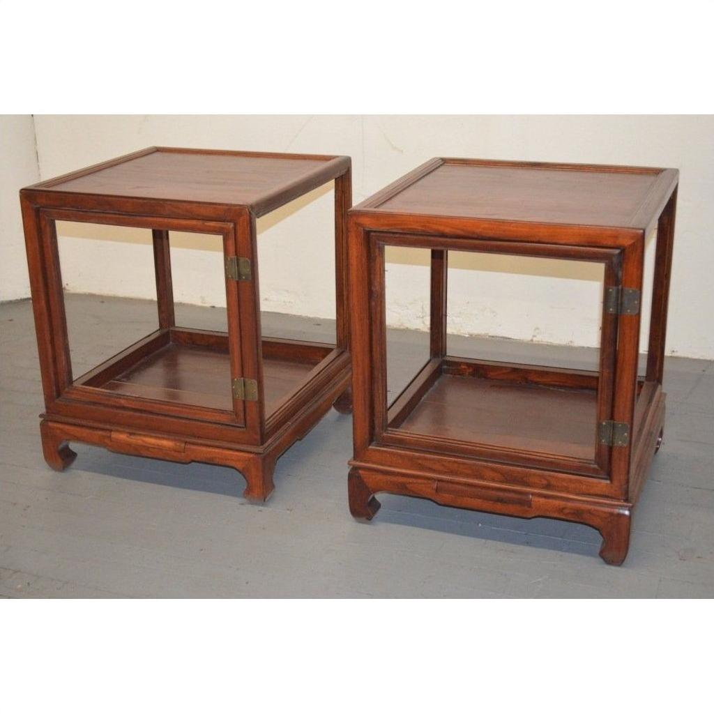 Pair of light wood Elmwood side tables with open sides, lower shelves, and hinged doors on a gray floor.