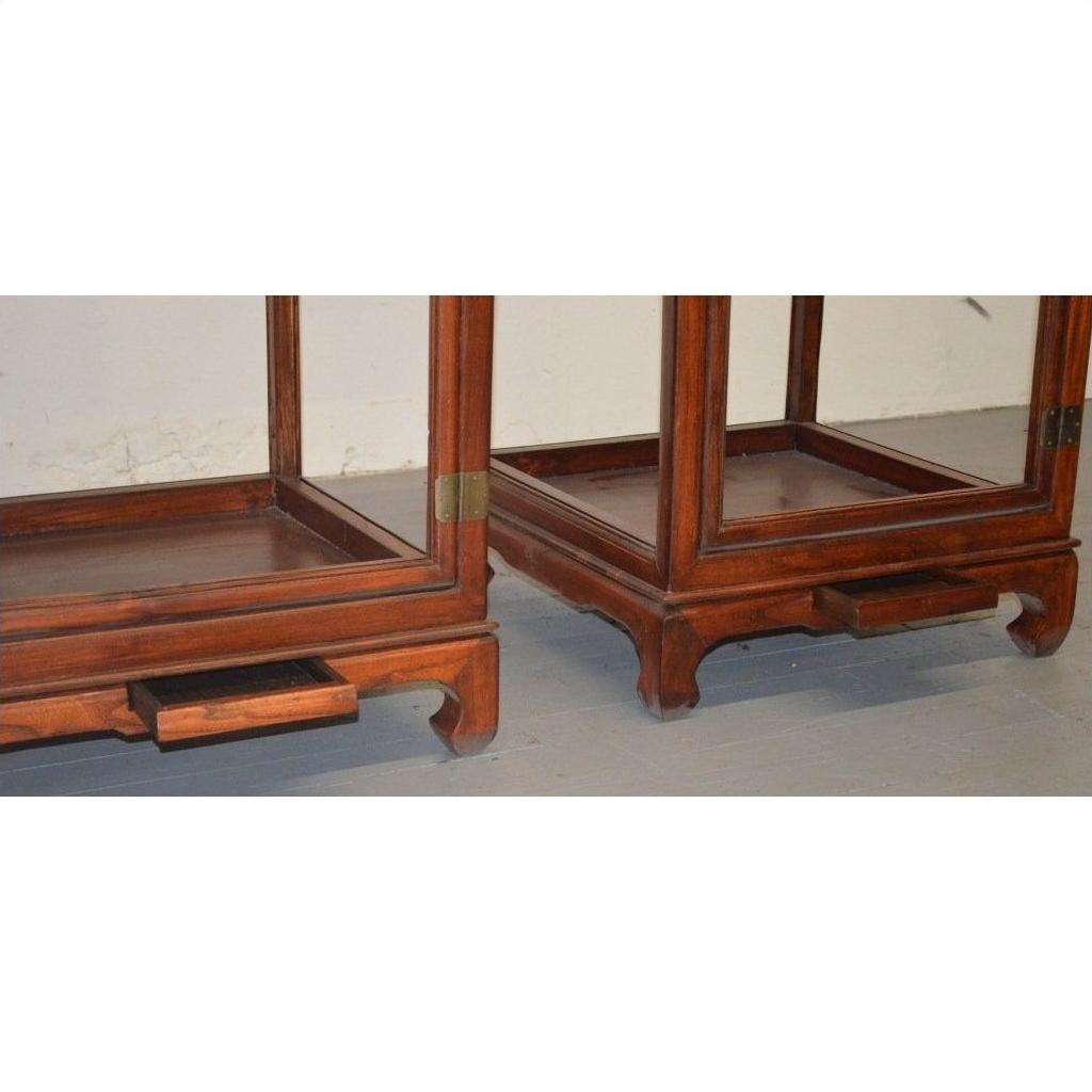 Brown Elmwood side tables with carved legs and pull-out trays, placed on a light-colored floor.
