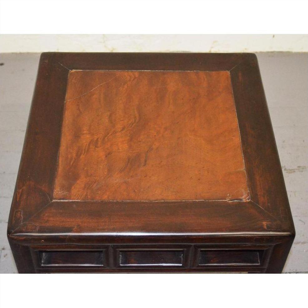 Dark brown elmwood stool with burl wood inlay and simple raised border, close-up view.
